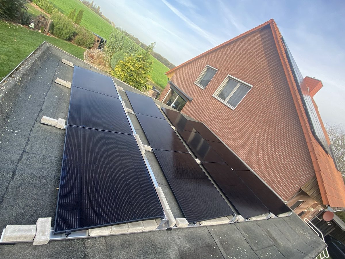 Solarmodule auf einem Flachdach mit freiem Feld im Hintergrund