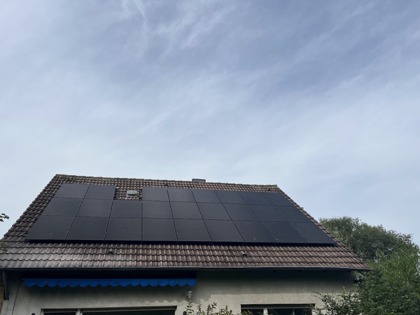 Schwarze Solarmodule auf einem Hausdach unter bedecktem Himmel