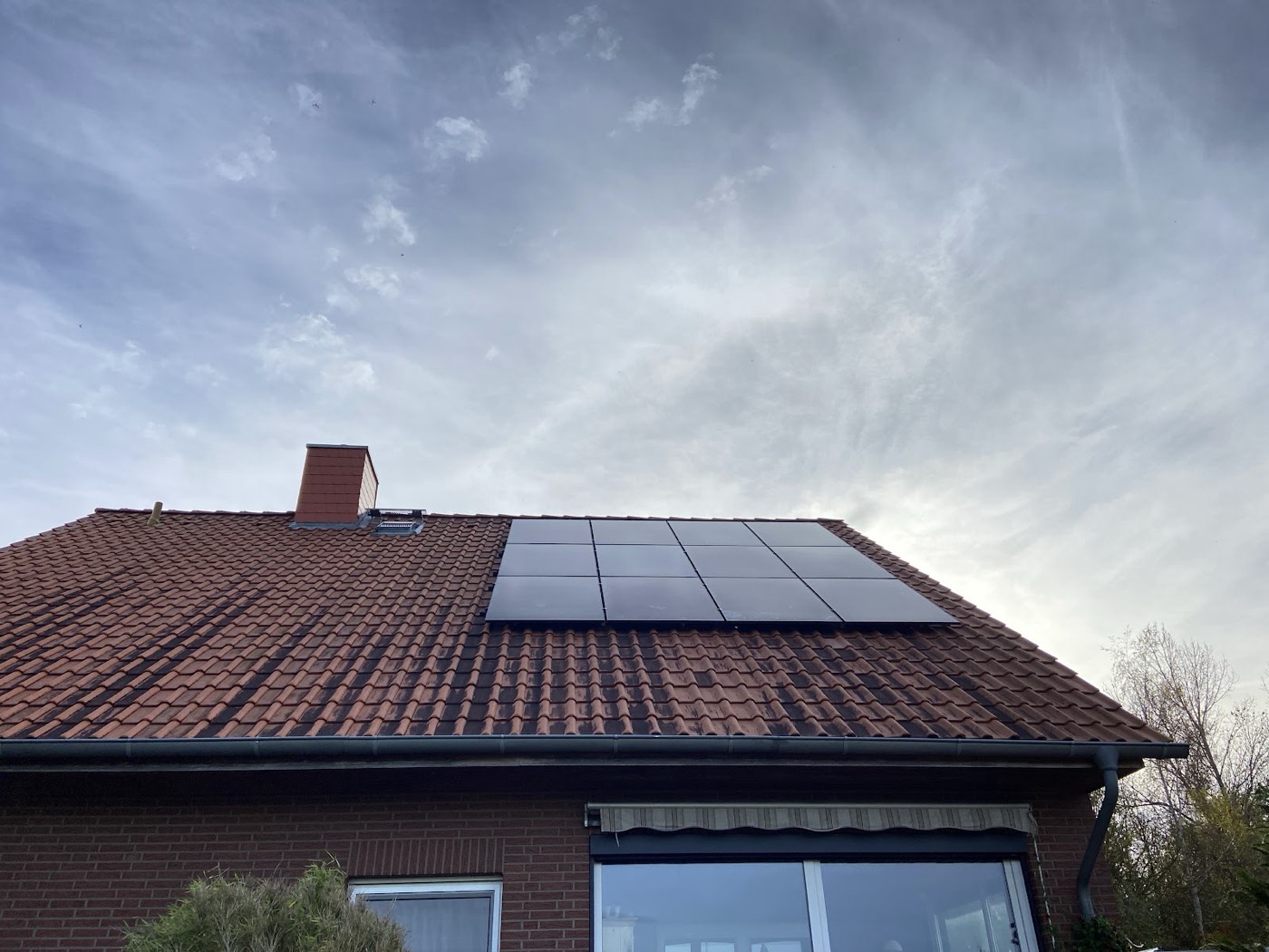 Photovoltaikanlage auf einem Backsteinhaus mit Dachfenster