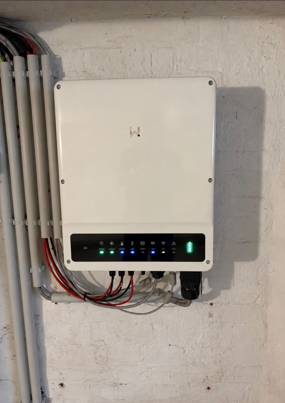Wechselrichter einer Solaranlage mit Betriebsanzeigen und sauber geführten Leitungen an einer weißen Wand